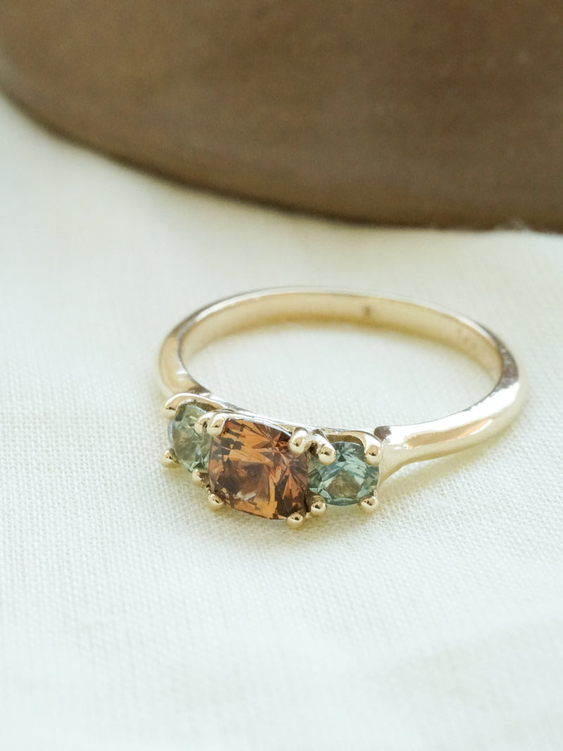 Shown: BIZARRE Y - $2500 - One of a kind Vega 3 Stone Ring. Unique 0.75ct orange/brown/purple center stone with green side stones. 14k yellow gold. Smooth texture. Polish finish. Size 6. 