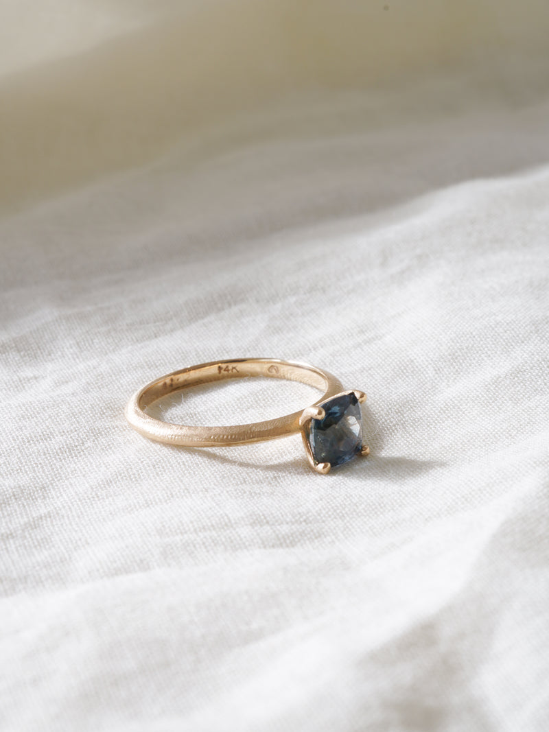 Shown: BIZARRE H - $2090 - Sage Solitaire with a 0.75ct cushion cut teal Montana Sapphire. 14k yellow gold. Organic texture. Matte finish. Size 6